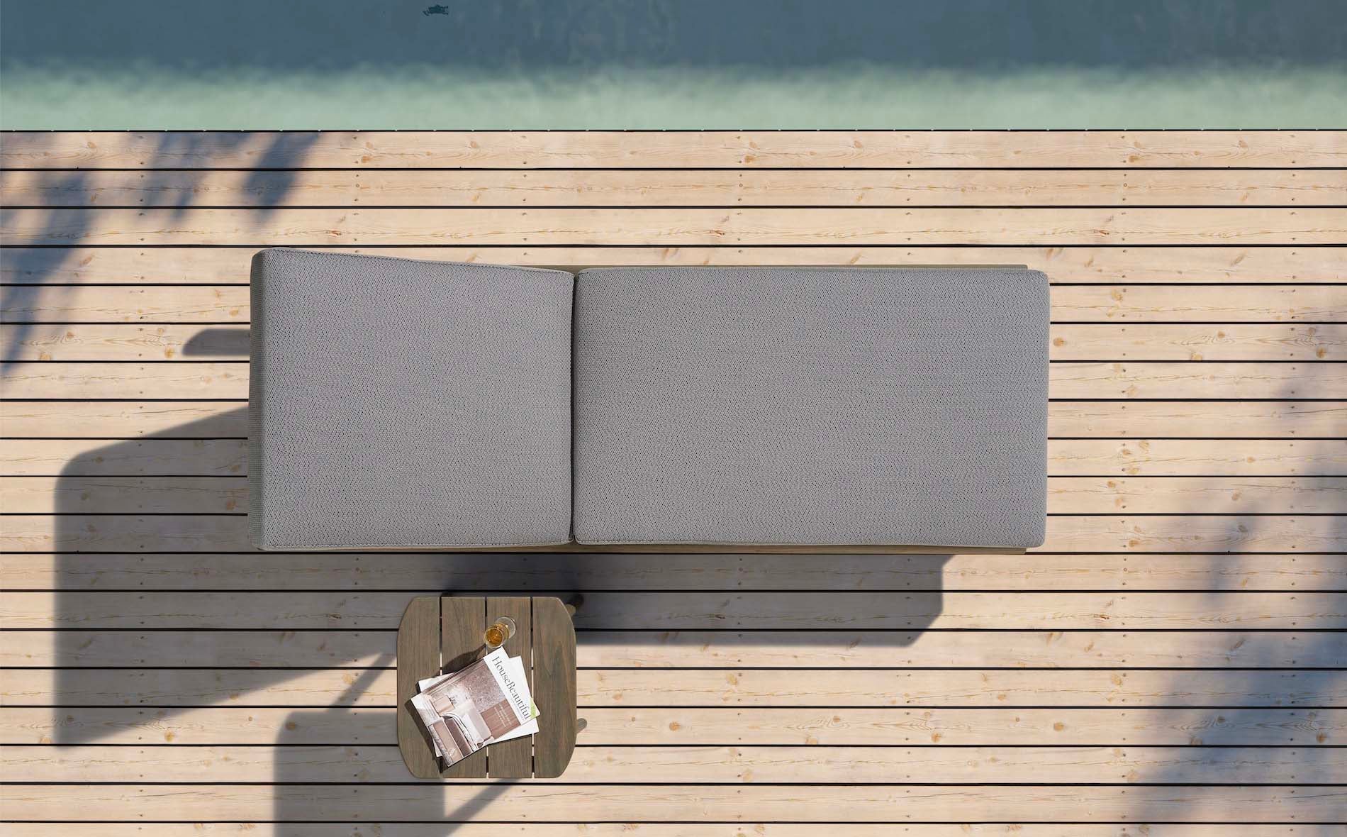 Bain de soleil luxueux en teck FSC avec mousse Quick Dry Foam grise et table d’appoint en bois assortie sur terrasse en bois.