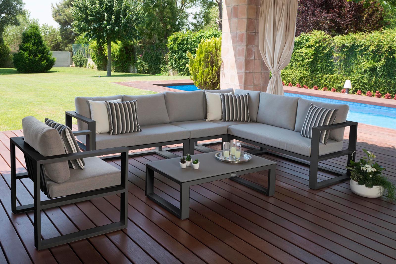 Salon de jardin d'angle modulable en aluminium noir, coussins gris élégants, design haut de gamme méditerranéen, ambiance.