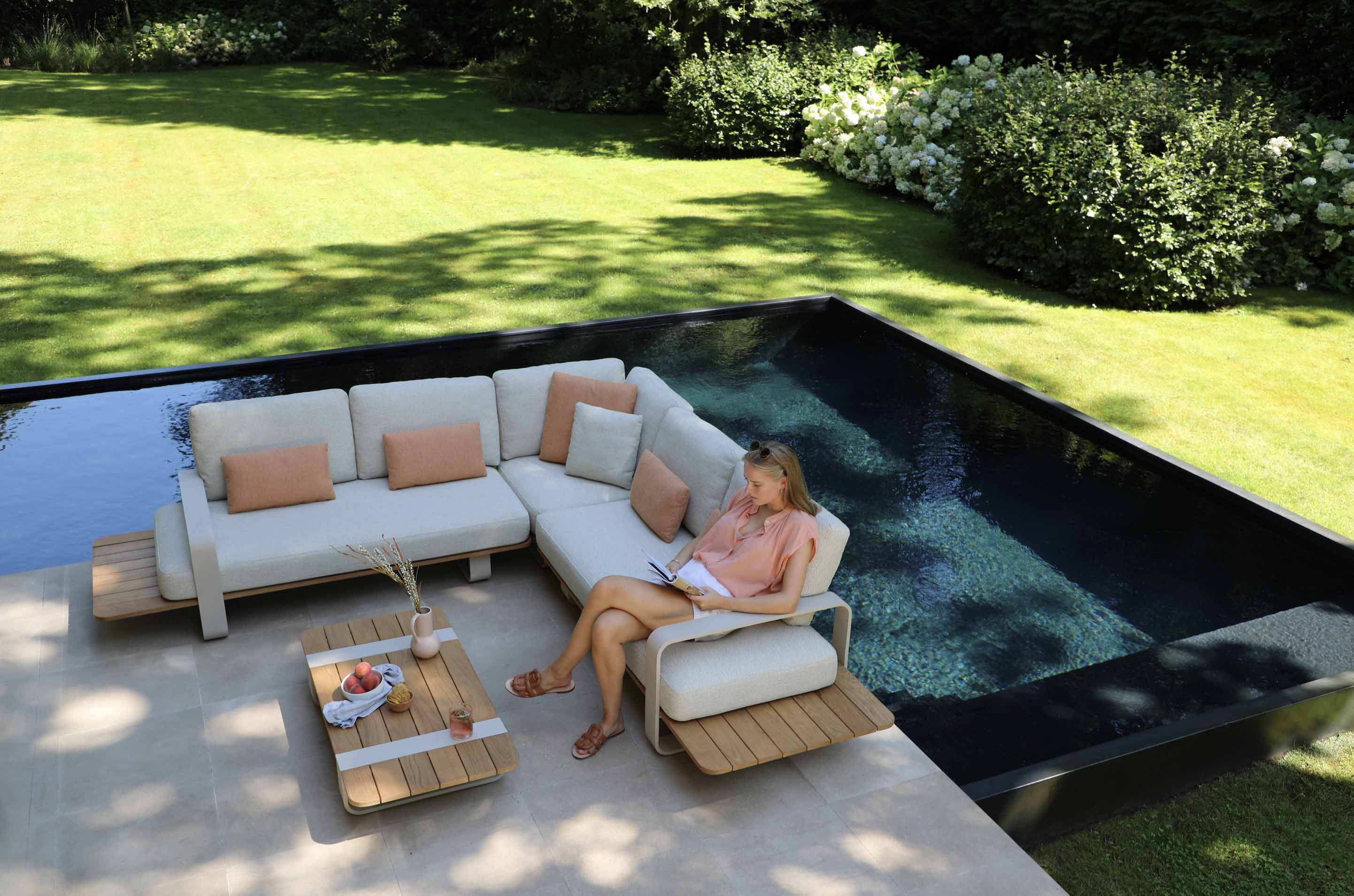 Salon de jardin d'angle en aluminium design et teck FSC, coussins en tissu 100% Sunproof Oléfine beige, ambiance luxe.