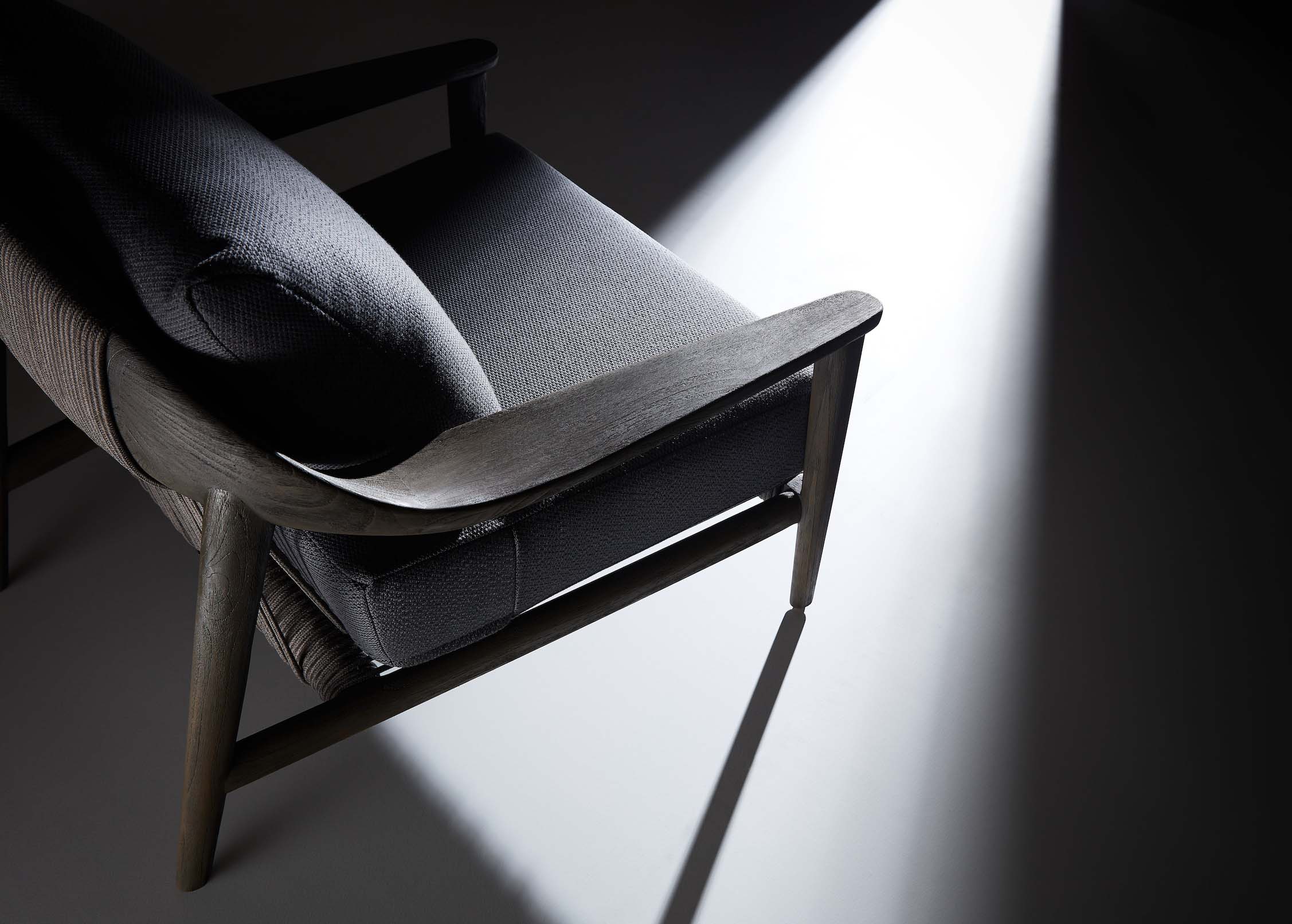 Fauteuil en teck FSC massif au design italien, corde tressée grise, coussin noir en Mousse Quick Dry Foam luxueux, ambiance.