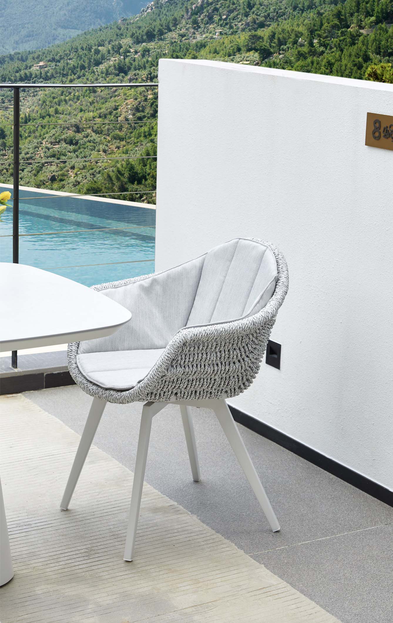 Fauteuil repas extérieur blanc en aluminium haut de gamme avec résine tressée et coussins, design élégant méditerranéen.