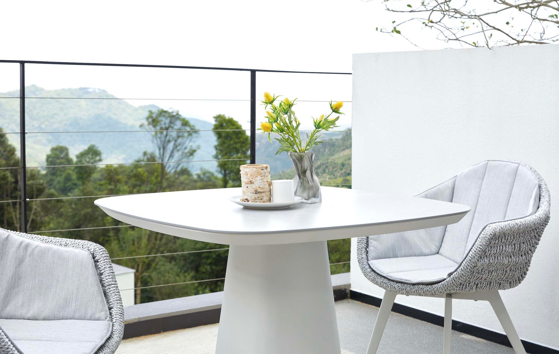 Table carrée en aluminium haut de gamme avec plateau céramique blanc, piètement central époxy, chaise en teck FSC et corde.