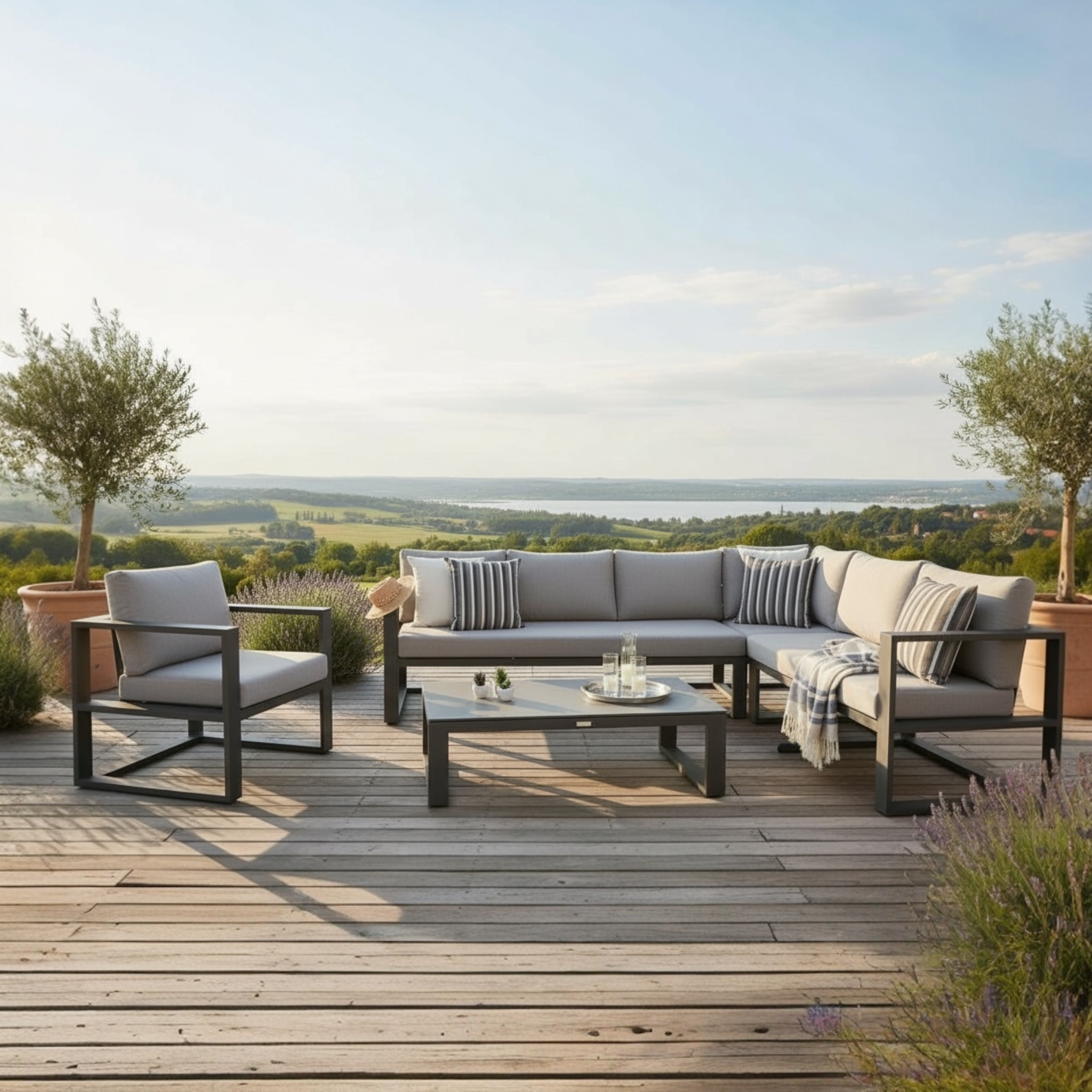 Salon modulable d’extérieur haut de gamme en aluminium noir avec coussins beiges et décoration méditerranéenne sur terrasse.