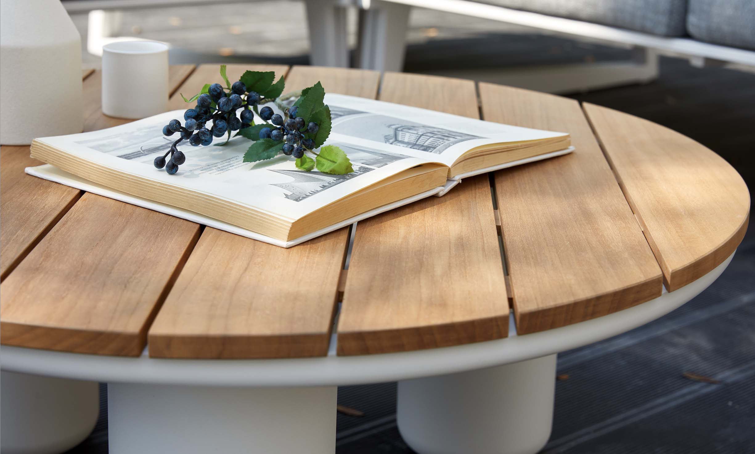 Table ronde en Teck FSC authentique avec surface lisse, structure aluminium inoxydable blanche, design luxe et élégant.