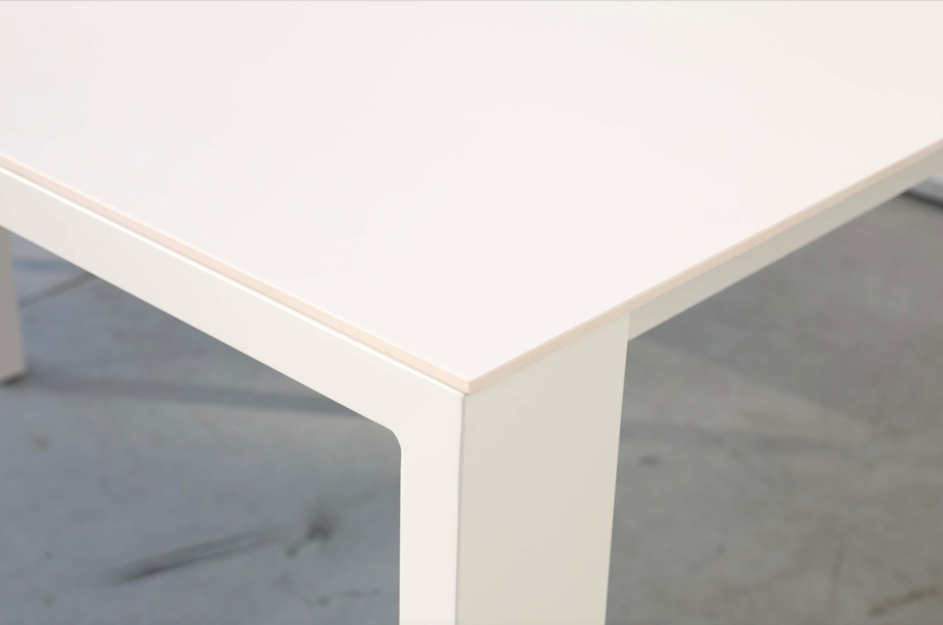 Détail d'angle de table de jardin COMO en aluminium haut de gamme blanc avec plateau en céramique lisse, design épuré.