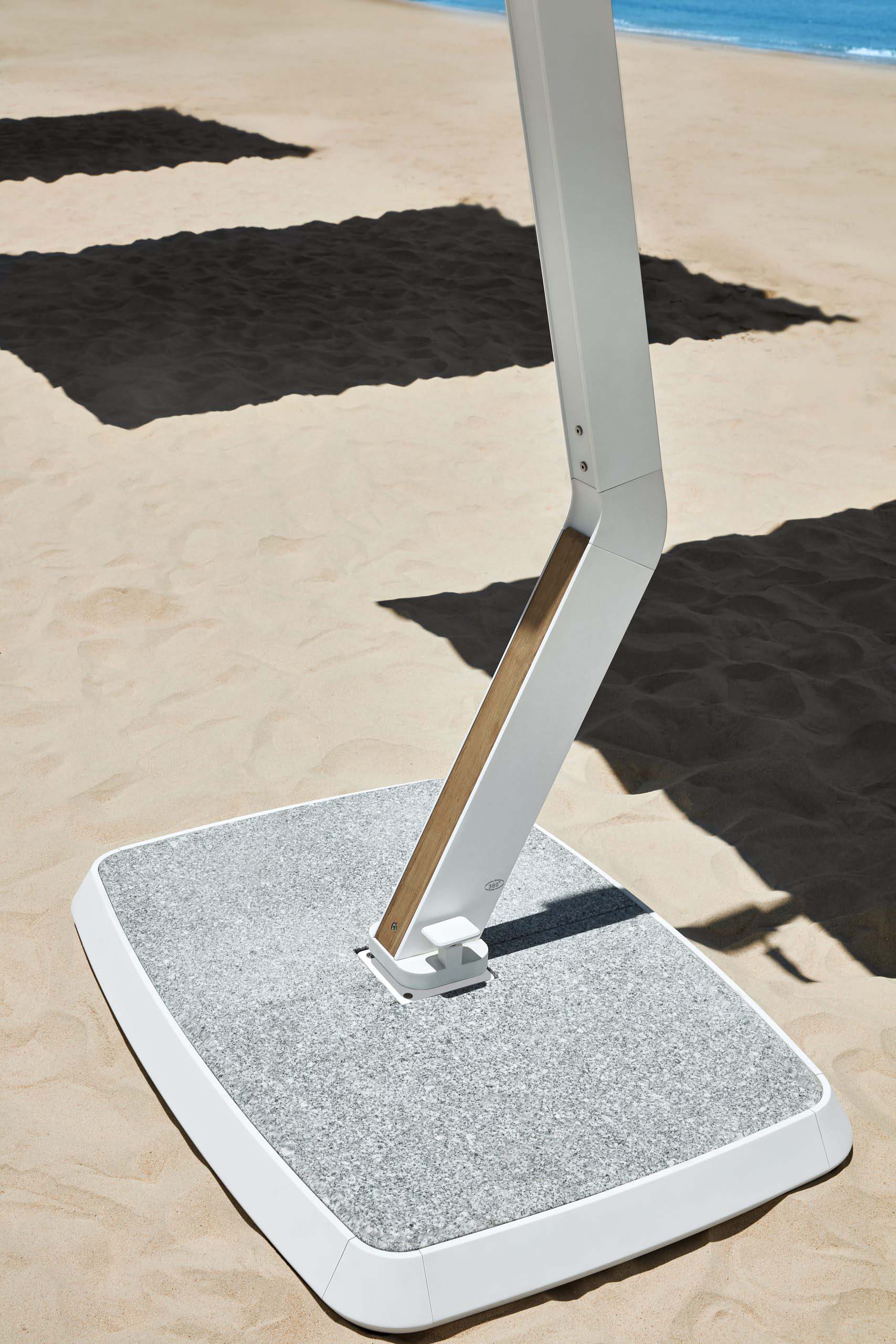Base en marbre blanc moderne supportant un mât aluminium blanc avec détail en teck FSC haut de gamme, alliant légèreté.