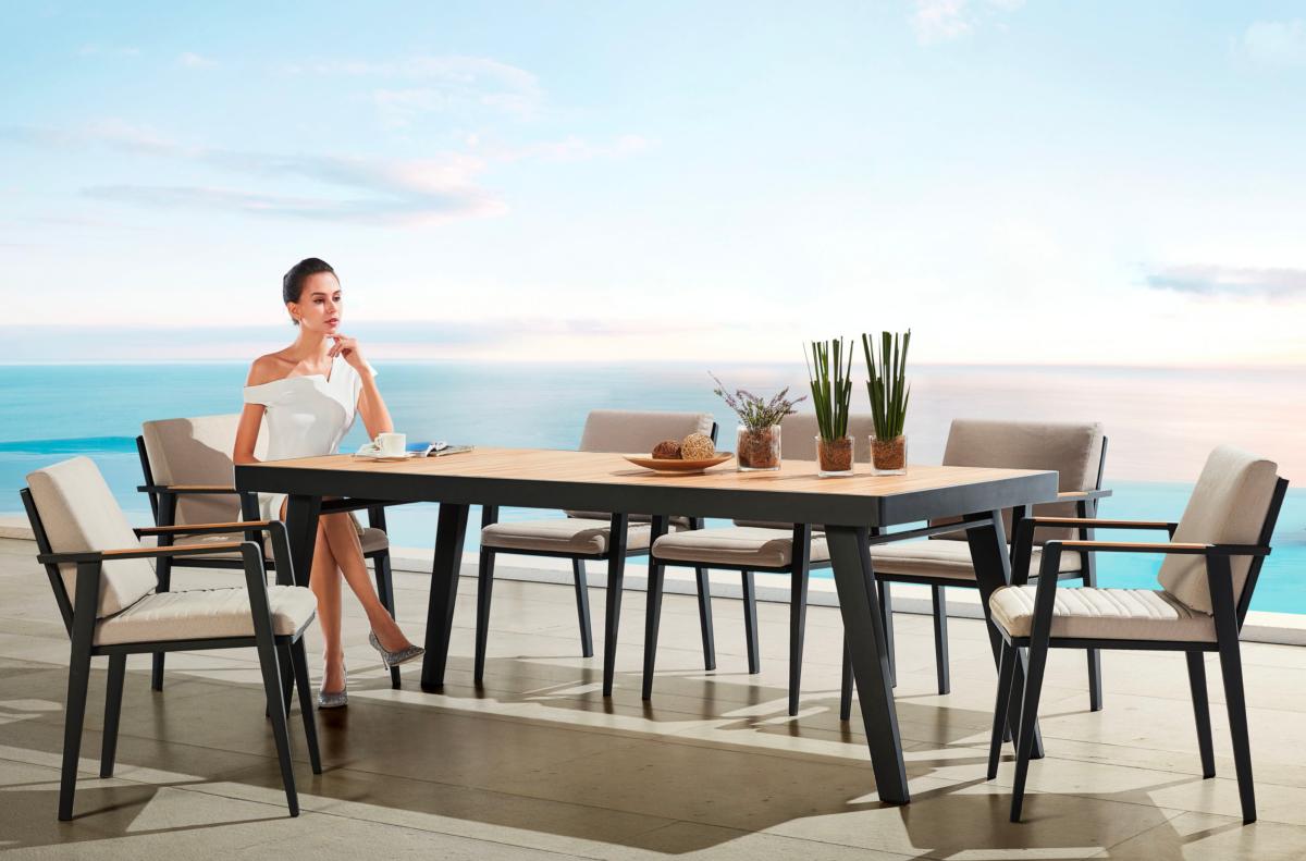 Ensemble repas 8 places avec table teck FSC et structure aluminium haut de gamme, chaises au design élégant équipées de coussin.