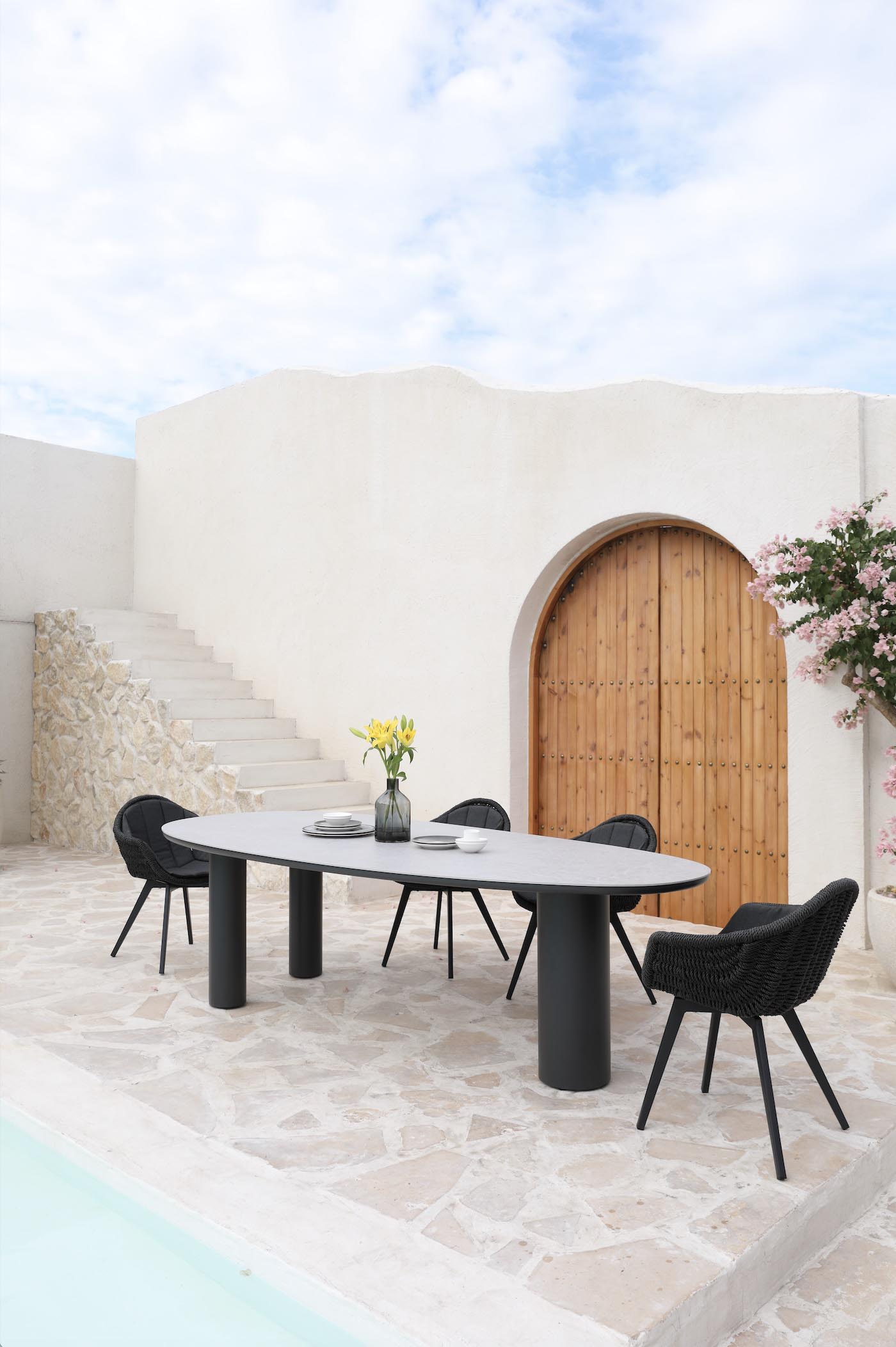 Fauteuil repas extérieur en aluminium haut de gamme et résine noire tressée avec coussins, design luxe méditerranéen. 