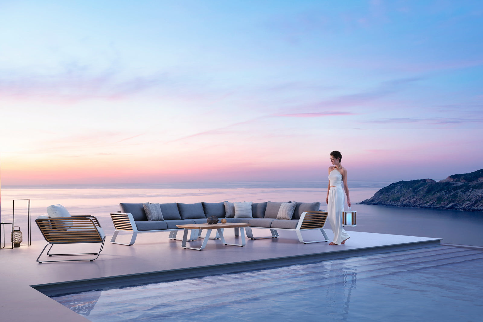Canapé d'angle en aluminium léger et teck FSC, design Pininfarina luxueux, coussins gris haut de gamme sur terrasse.