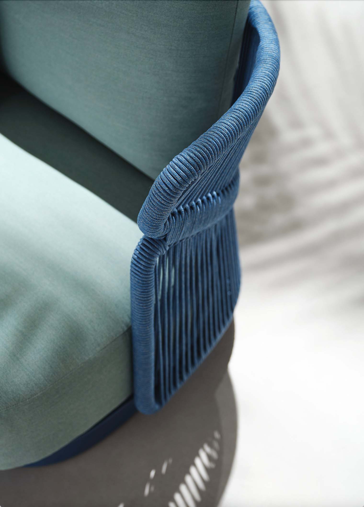 Détail d'accoudoir en corde tressée bleu provençal sur structure aluminium, coussin oléfine bleu, style luxueux designer.