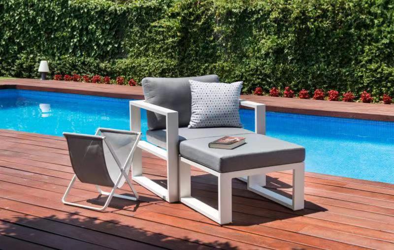 Fauteuil modulable haut de gamme en aluminium blanc avec coussins gris clair, repose-pied assorti, design élégant. 