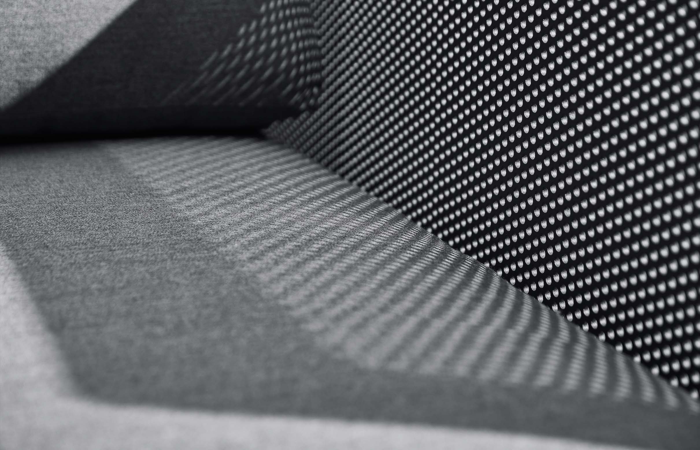 Détail de coussin en tissu Oléfine gris foncé, structure en aluminium thermolaqué noir, mousse QuikDry, textile respirant.