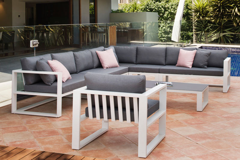 Banquette modulable en aluminium haut de gamme avec coussins gris et coussins décoratifs roses, design épuré et élégant. 