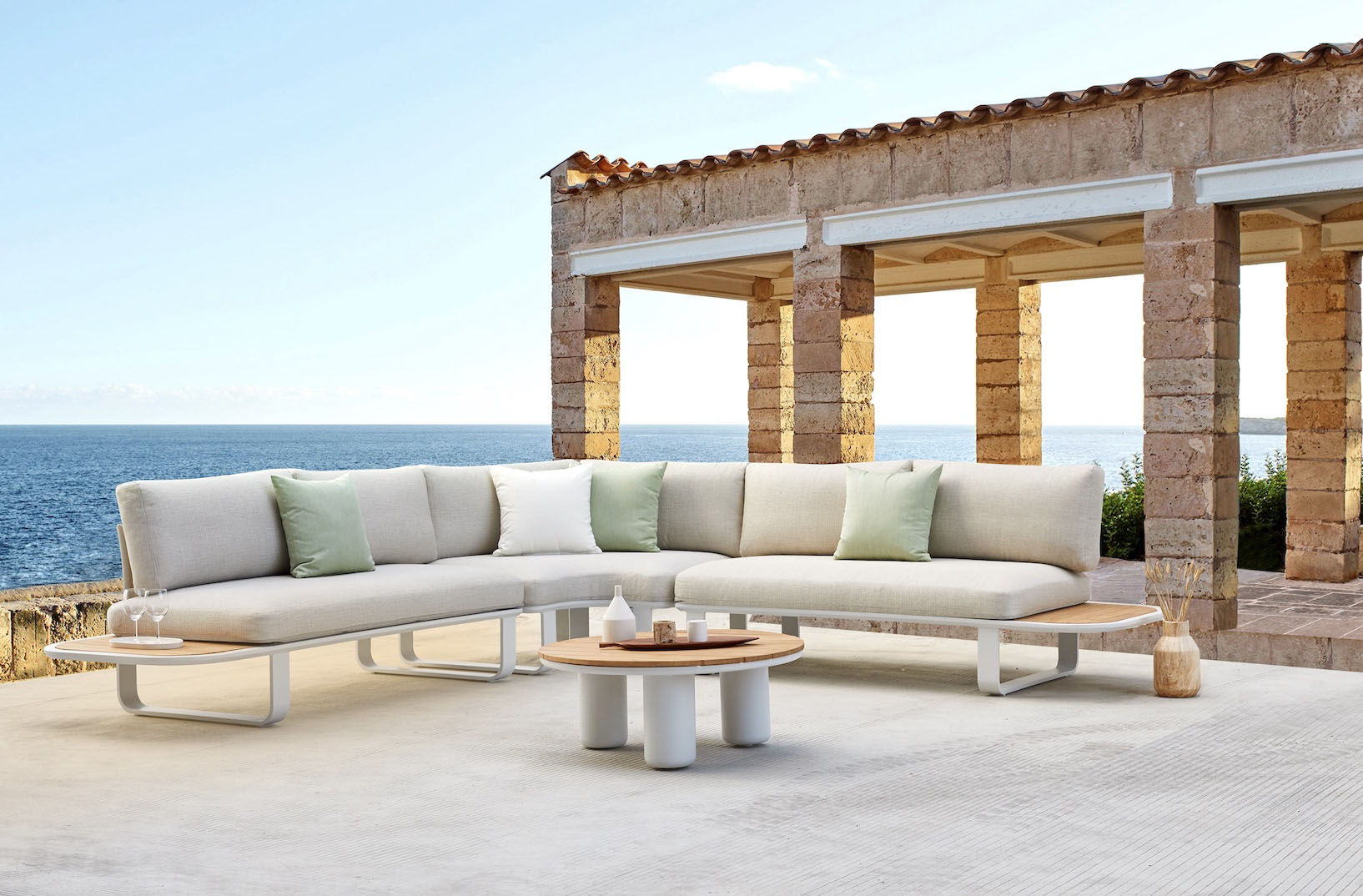 Salon de jardin d'angle haut de gamme en aluminium, coussins mousse Quick Dry Foam blanc cassé, table basse céramique ronde. 