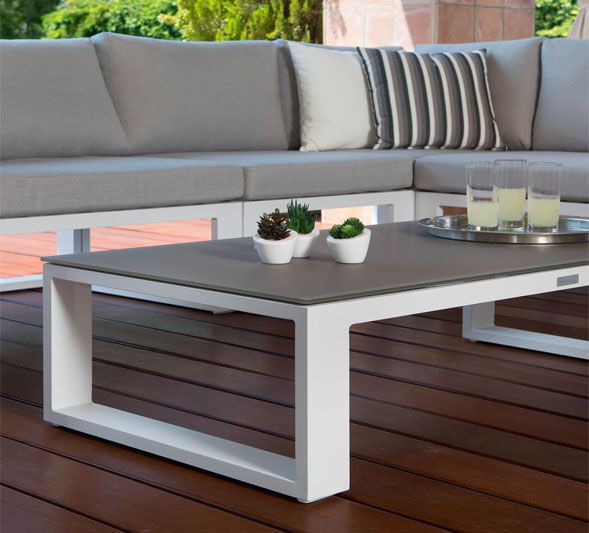 Canapé d’angle modulable en aluminium blanc haut de gamme avec coussins gris, table basse blanche élégante. 