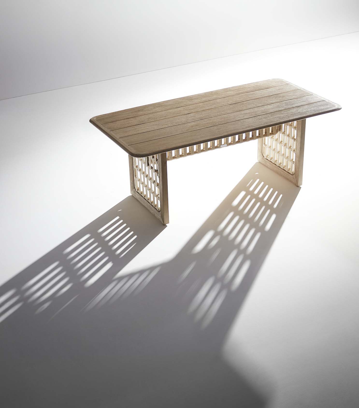 Table de jardin luxe en teck FSC avec pieds ajourés en corde tressée, design italien élégant, ombres délicates, style.