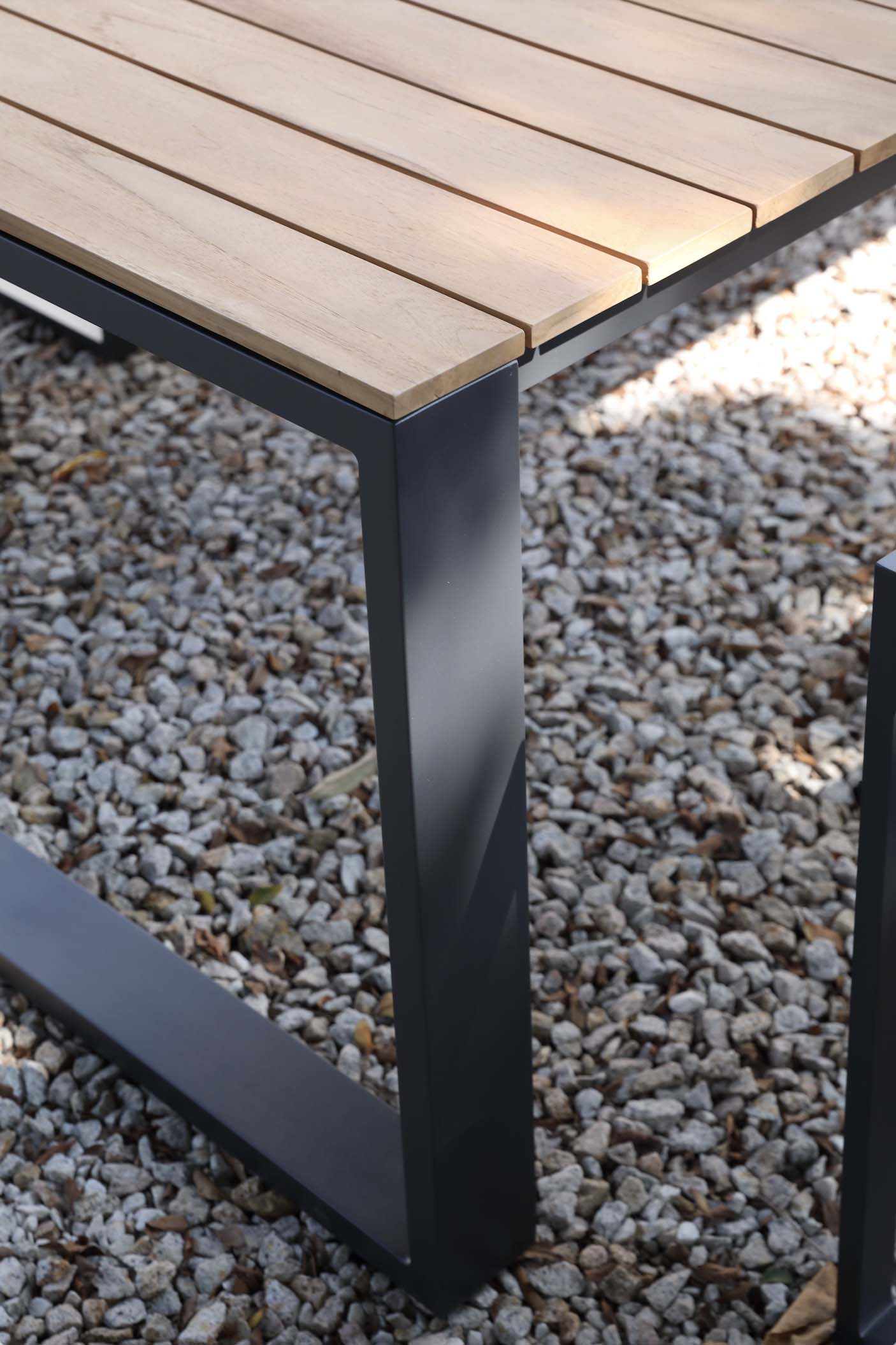 Table de jardin luxe avec plateau en teck FSC naturel aux lames fines et pieds en aluminium haut de gamme noir mat, design.