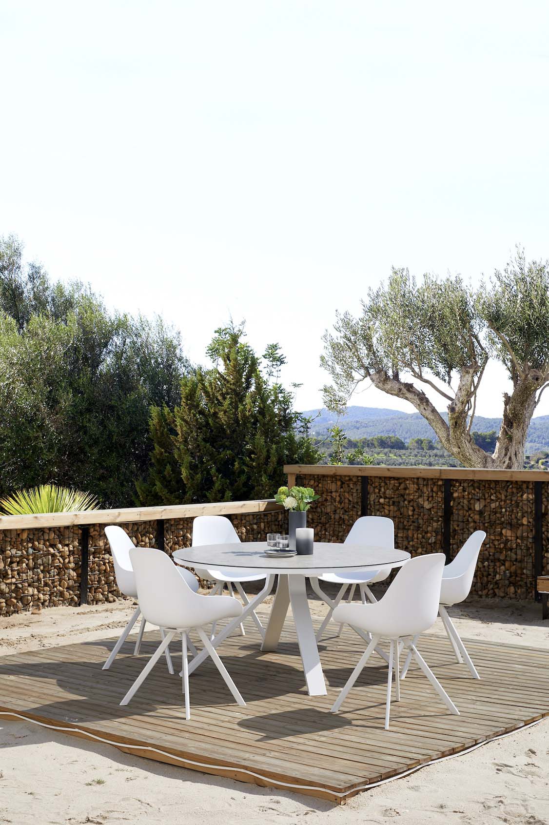 Table ronde en aluminium haut de gamme blanc avec plateau en verre sécurit, finition peinture époxy, entourée de quatre chaises.