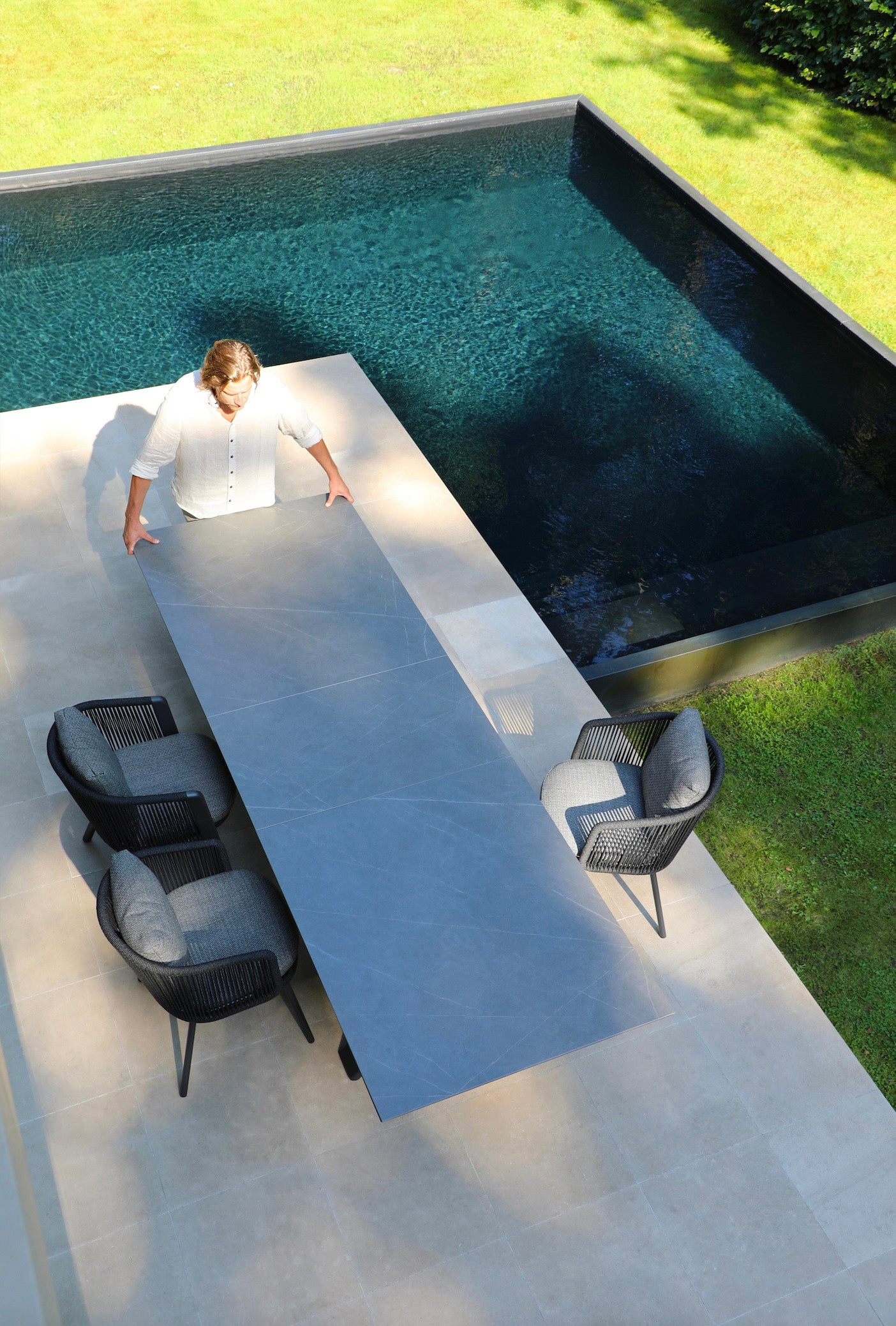 Table extensible avec plateau céramique gris élégant et structure en aluminium haut de gamme inoxydable, grands fauteuils.