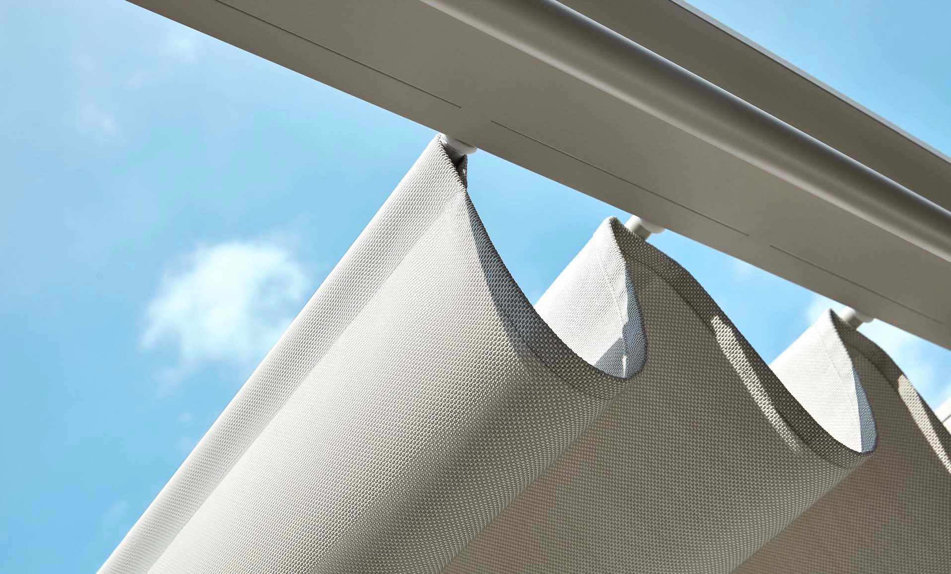 Toile blanche déperlante tendue sur structure extérieure moderne en aluminium, ambiance élégante et méditerranéenne.